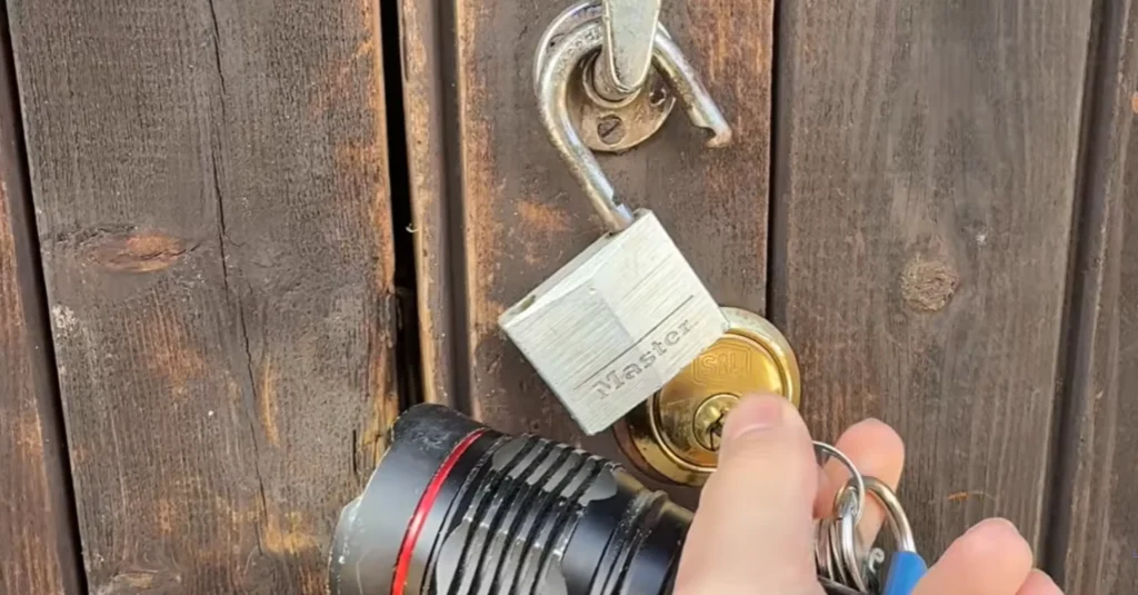 Padlock on a wooden gate with a flashlight and keys
