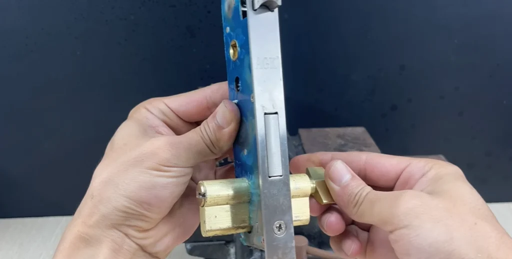 Hands fitting a brass cylinder into a mortise lock body