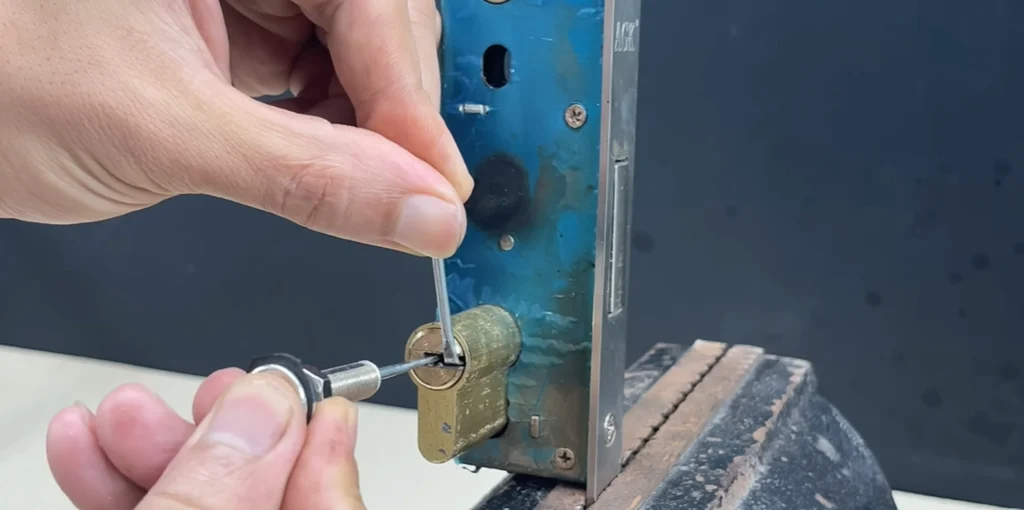 Locksmith picking a lock cylinder held in a vise